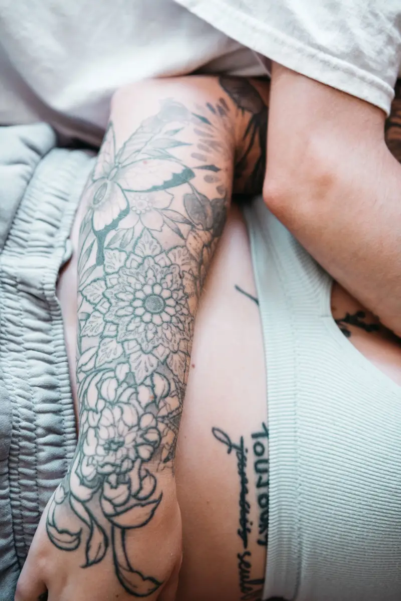 Floral sleeve and a line of script on a person's arm and side